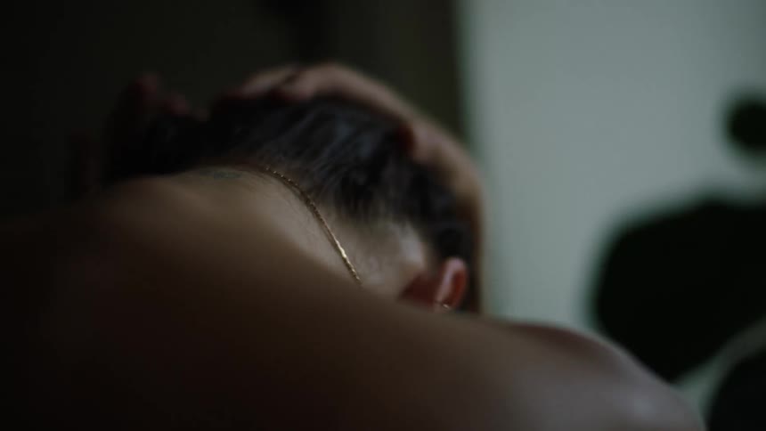 A woman has her head leaning forward as she touches her hair