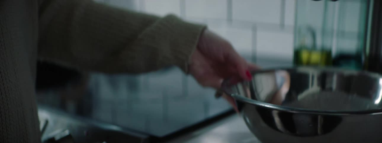 A woman whisks flour and egg in a metal mixing bowl