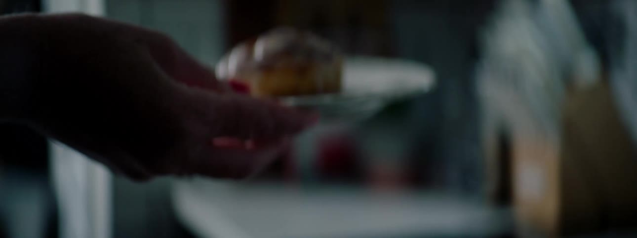 Womans hand takes a muffin with cream from the tray and puts it on a plate then grabs a cup of tea and walks to the table