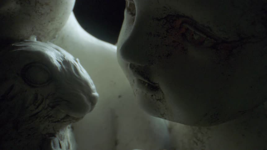 The statue of a child and animal sit in the dark