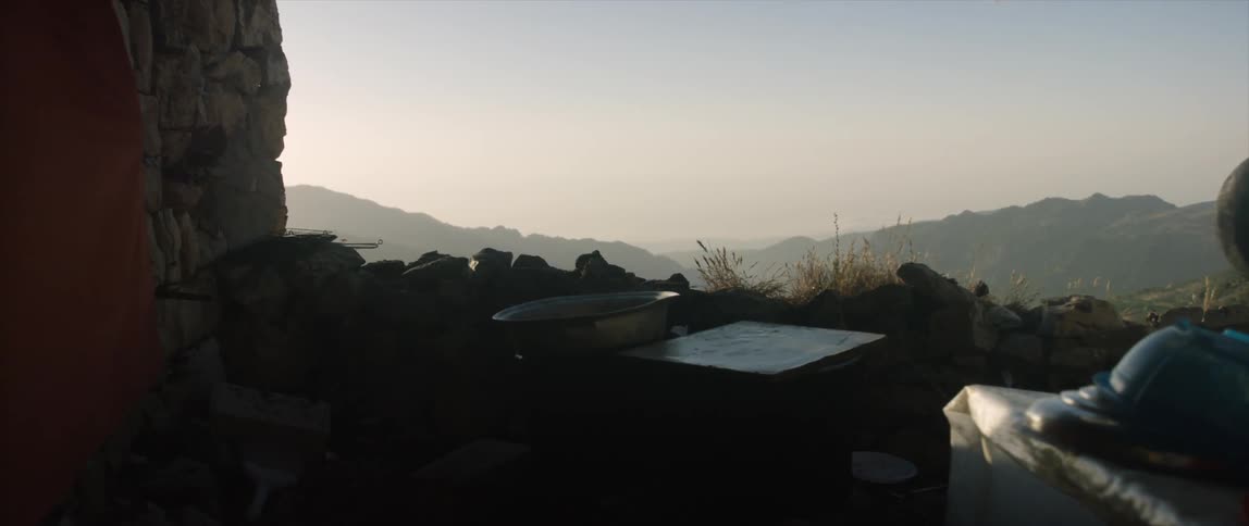 A terrace made of rock oversees a mountain range on a cloudy day