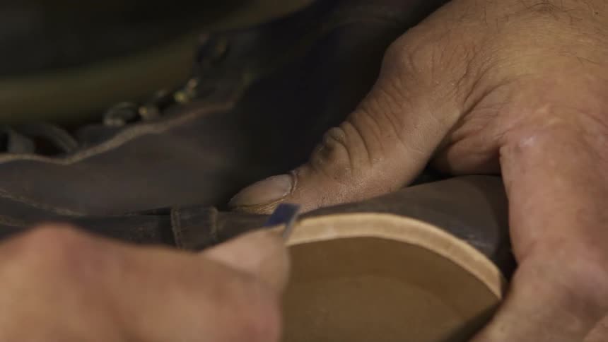 Close up of a man working on a sole of a shoe