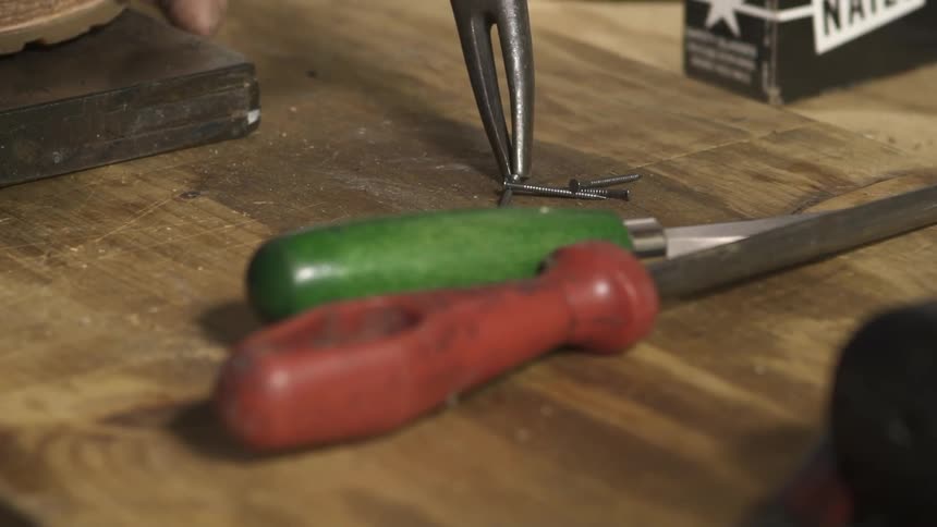 Close up of a tool picking up a small nail