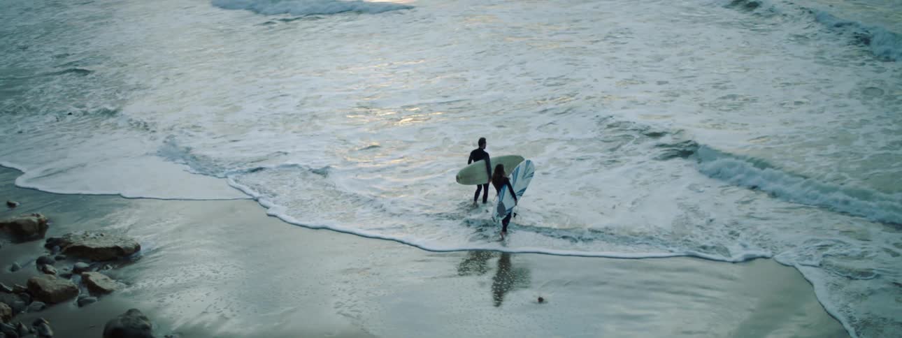 Two people are surfing on the ocean