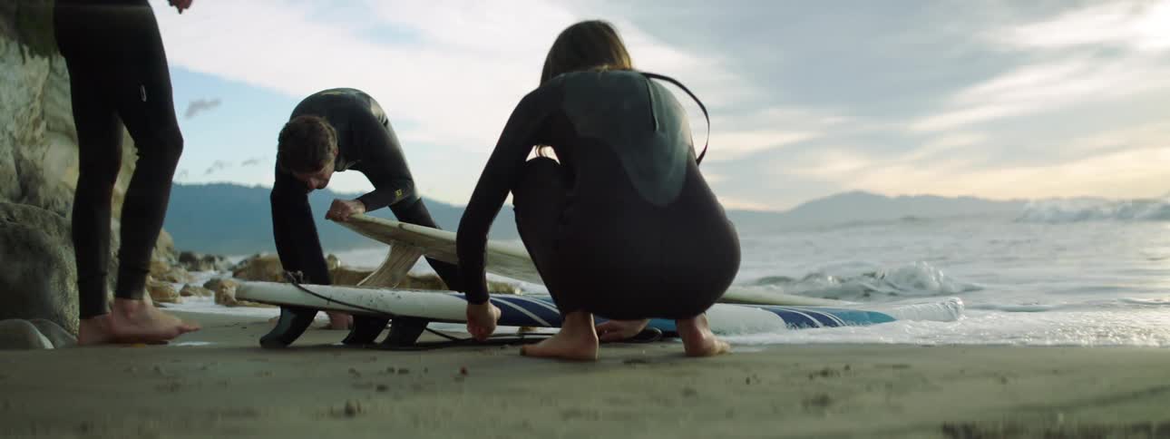 Surfers prep their boards on the beach