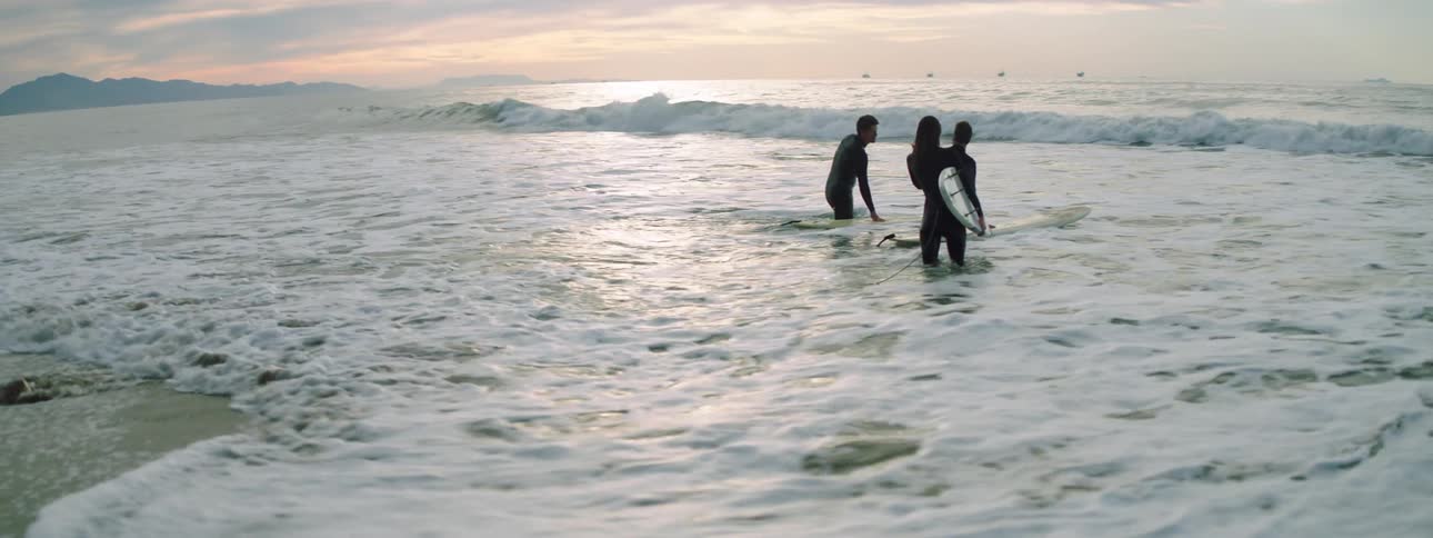 Three surfers enter the waves together