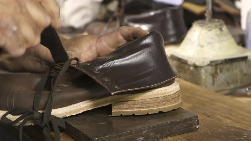A cobbler nailing a sole on a boot