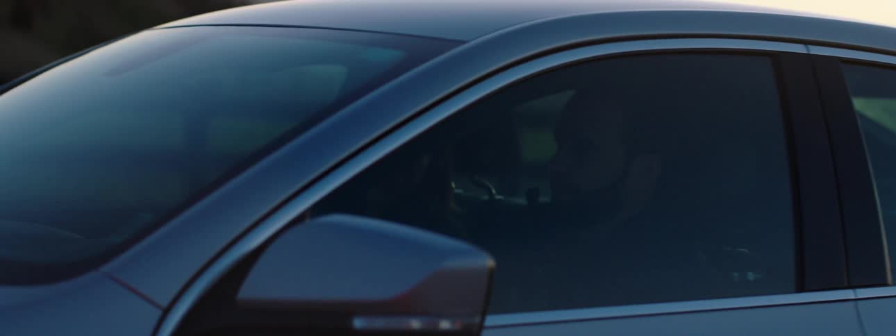 A couple drive a car on a rural road at sunset