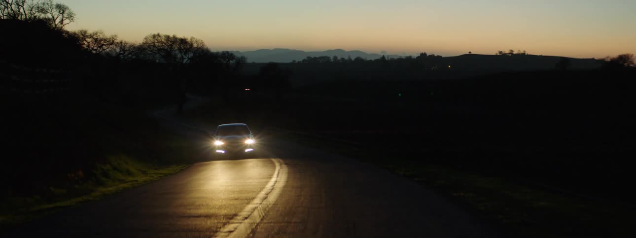 A car driving down a quiet road at night