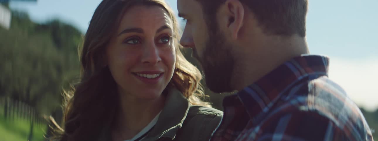 A man and woman are outdoors looking at a cell phone