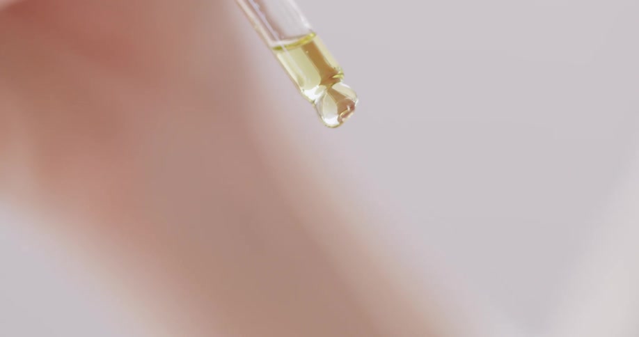 Close up of a hand holding a dropper and squeezing the liquid out of it