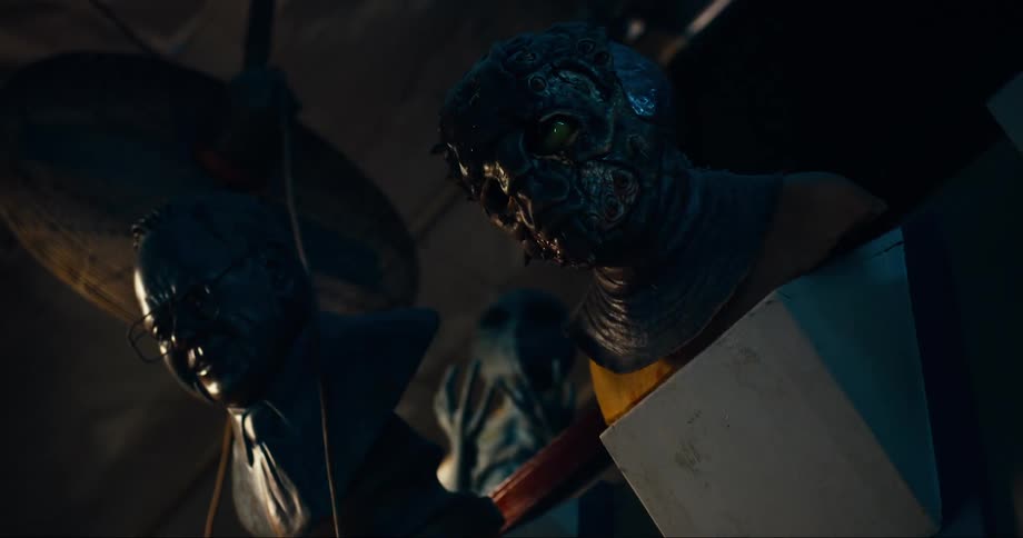 Two statues of heads are on display in the dark room