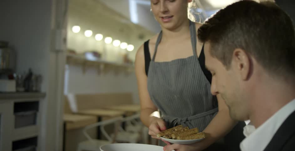 Woman serves breakfast for a male customer on a restaurant
