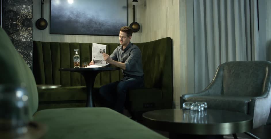 Man sits at a table reading a newspaper