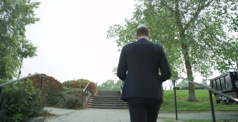 A man in a suit ascends stairs in a walkway in a public park