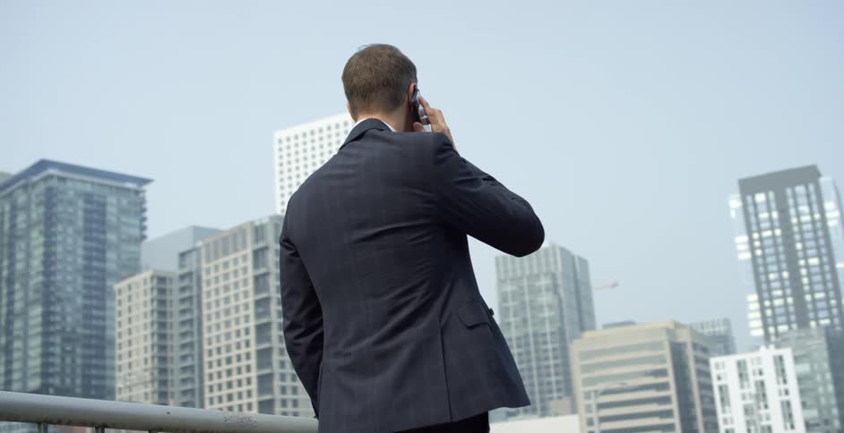 A man is walking through a downtown city while talking on a cellphone