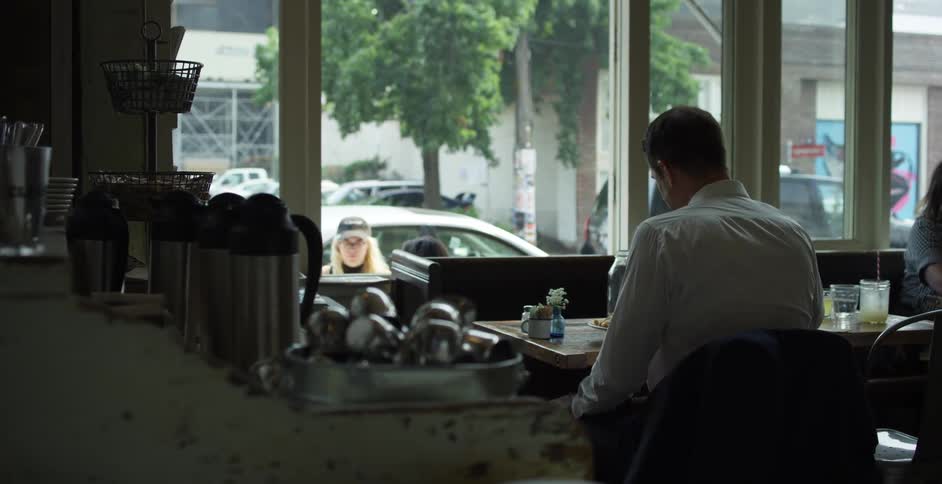 Man with a suit sitting at a table eats food in a cafeteria