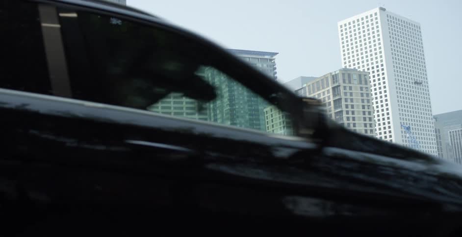 Man walks on a city sidewalk as cars travel by on the road