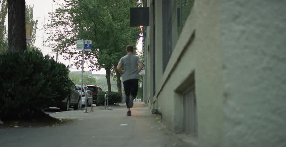 A man runs down the sidewalk of a smaller city
