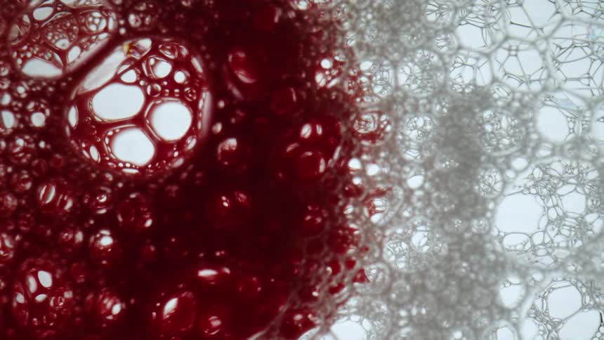 A red liquid pouring into foamy bubbles