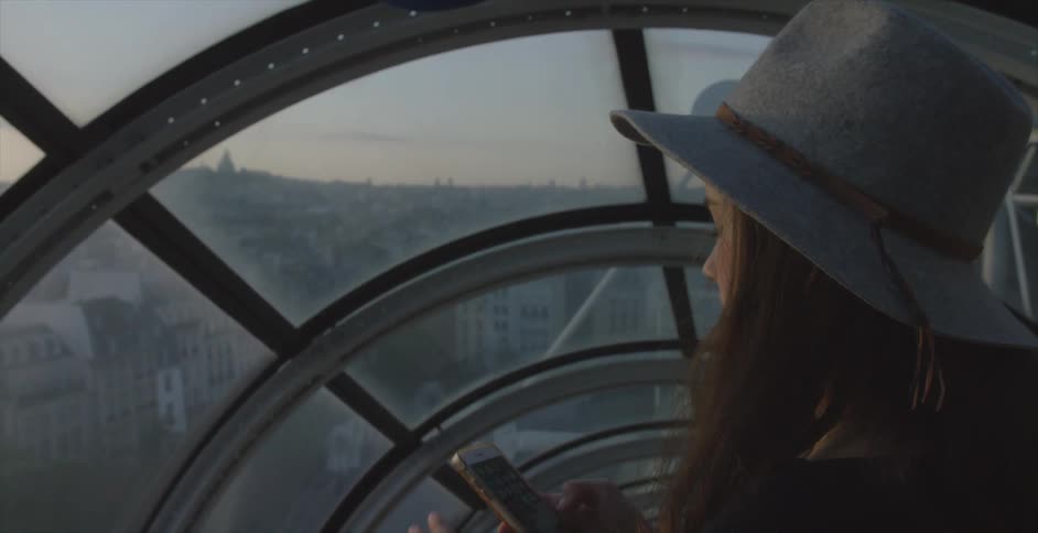 A woman is standing before a large window overseeing a city