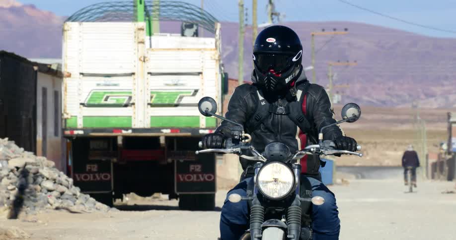 Motorcycle drives on the street of a slum at day