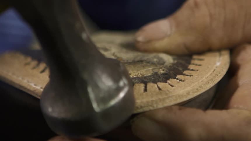 A person is using a tool to hammer a shoe