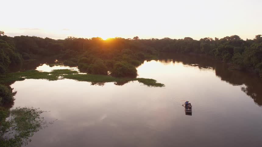 Boat rowing on a river through tropical forests at sunset