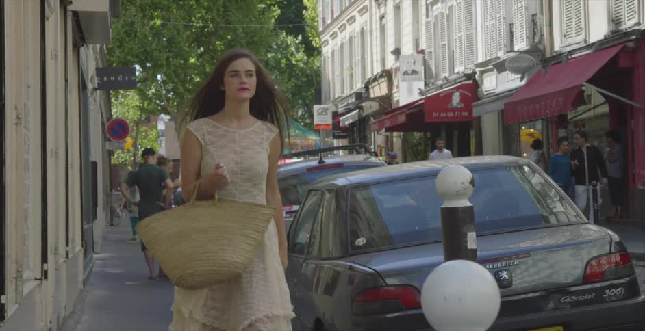 A woman walking down a city street that is lined with shops