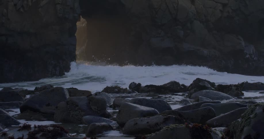 Ocean waves crash through rocks on a beach