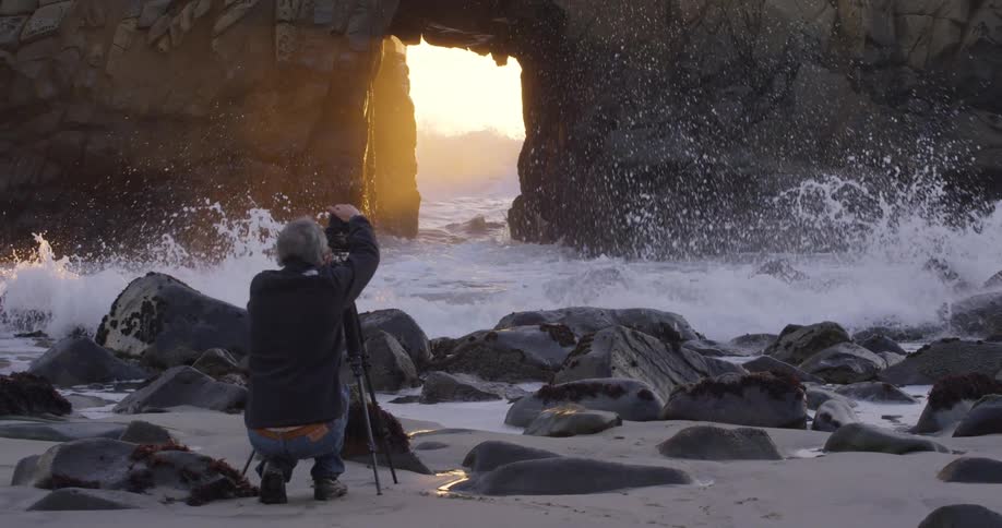 A man is photographing the waves passing through a sea cave