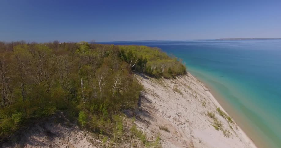 A hillside covered in trees leads to the shore