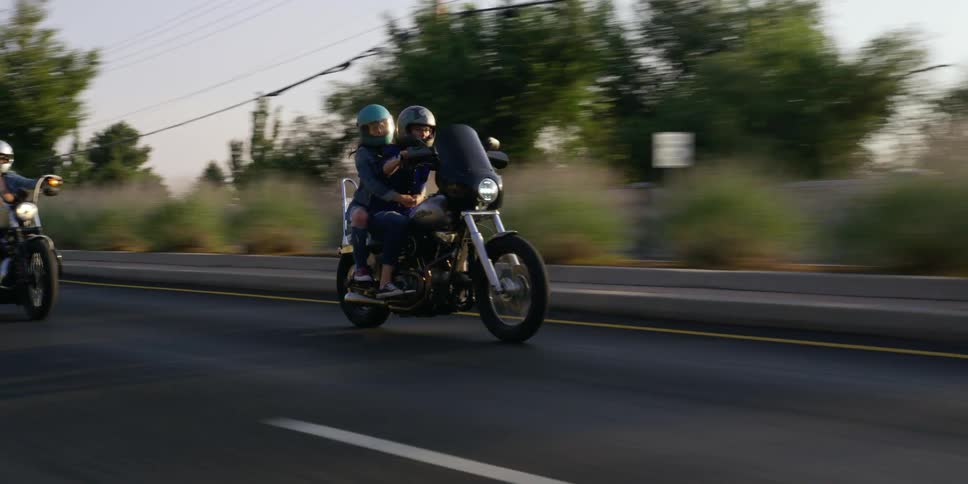 People with helmets riding motorcycles with trees and the sky in the background