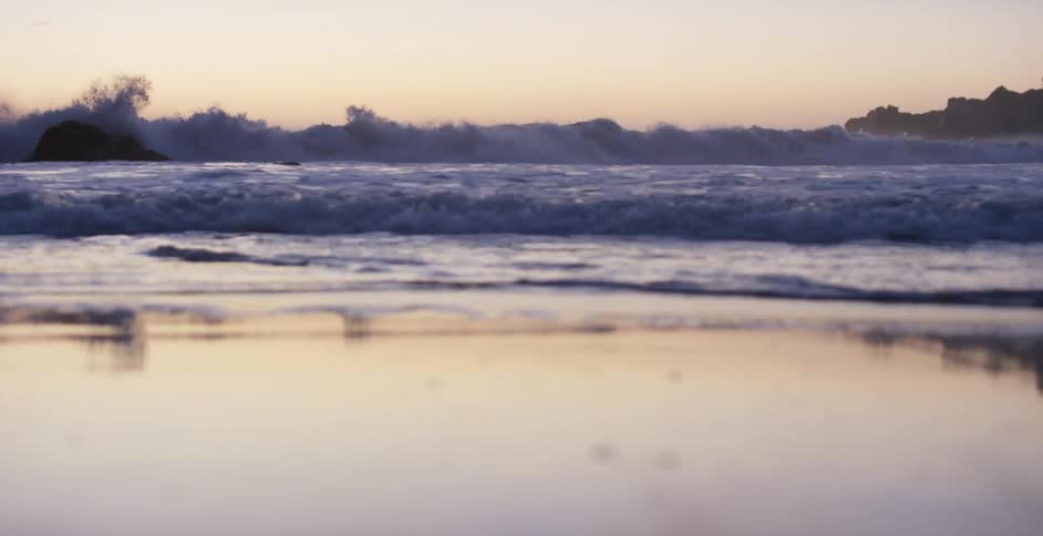 Ocean waves washing into a beach at sunset