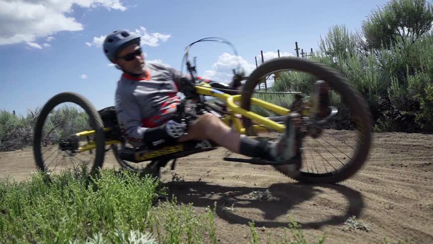 A man bikes on a sandy trail