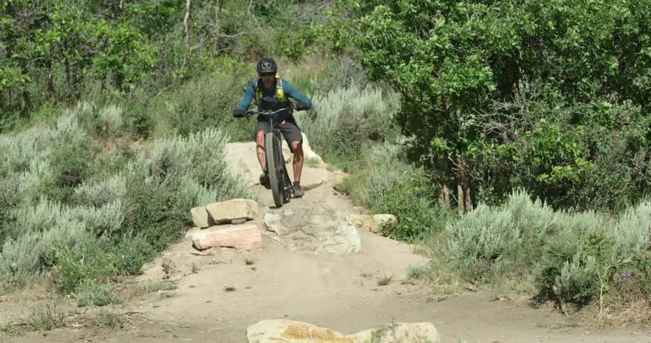 Man drives a bicycle through the rocks on a dirt path