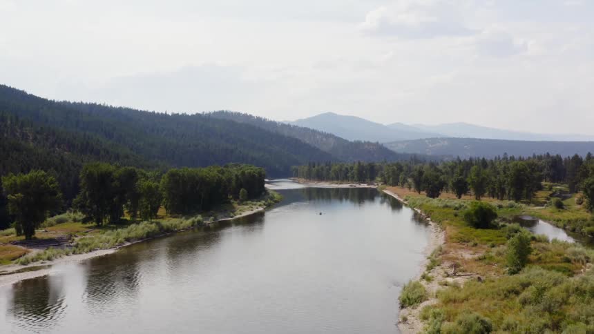 Landscape view of river with trees on the bank and hills in the distance