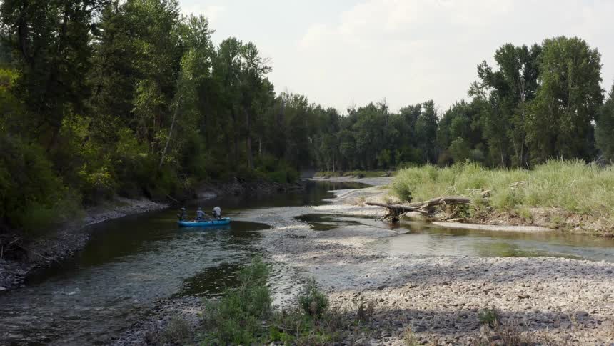Three people in a canoe going down a river