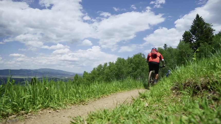 Cyclists driving mountain bikes down a trail at day