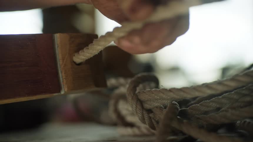 A person pulls a rope through a piece of wood