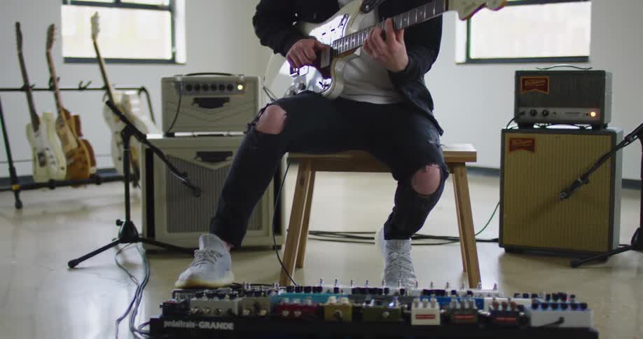 A man sits inside and plays the guitar