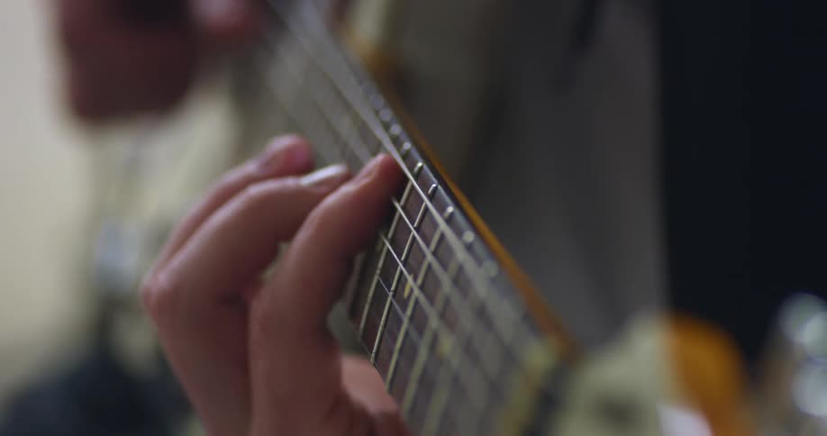 Man wearing a black long sleeve t shirt plays a guitar made of wood with six strings