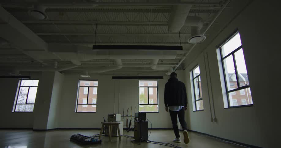 A man walks in to a room and picks up a guitar