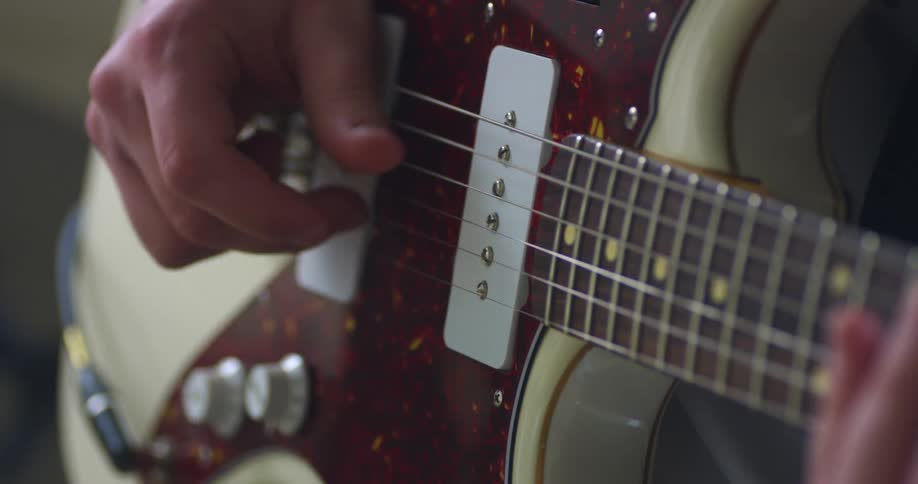 Man wearing a black long sleeve t shirt plays a guitar with six strings