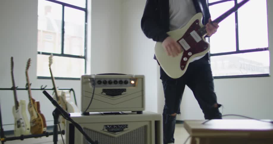 A man sits down to play an electric guitar