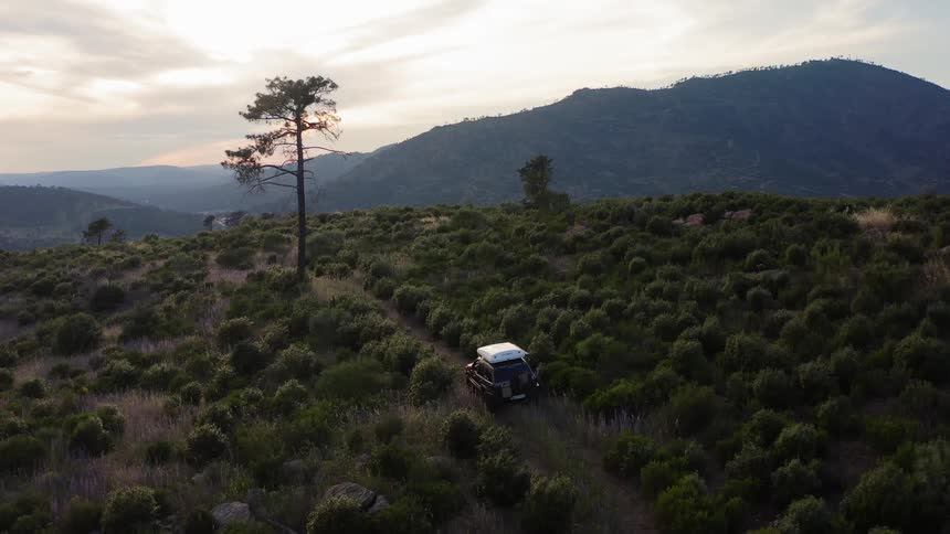 Vehicle travels on a dirt road near the mountains