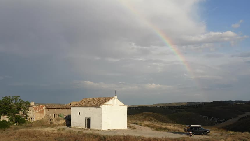 Aerial view of a rainbow over a small rural church in the hills