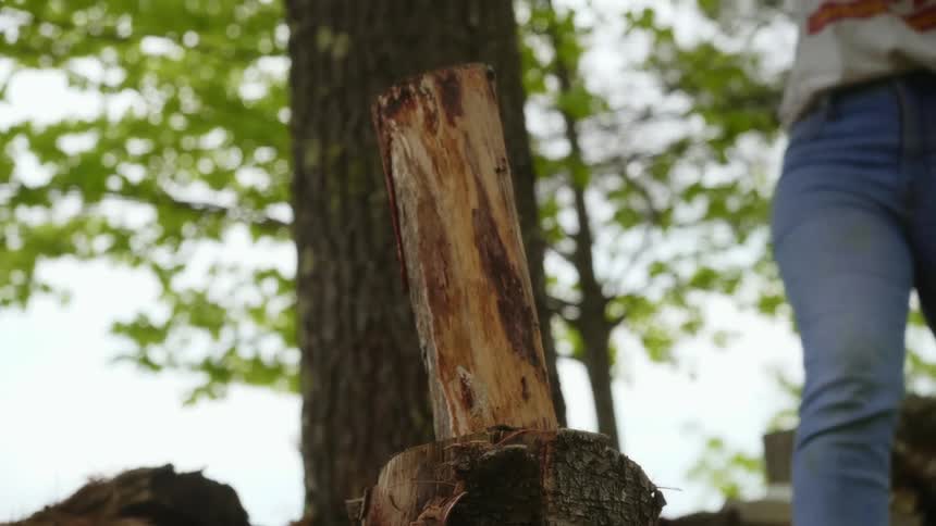 A woman chops wood outside