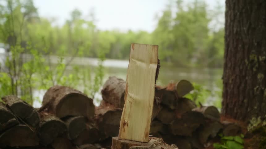 Ax chops wood in half outdoors near running water