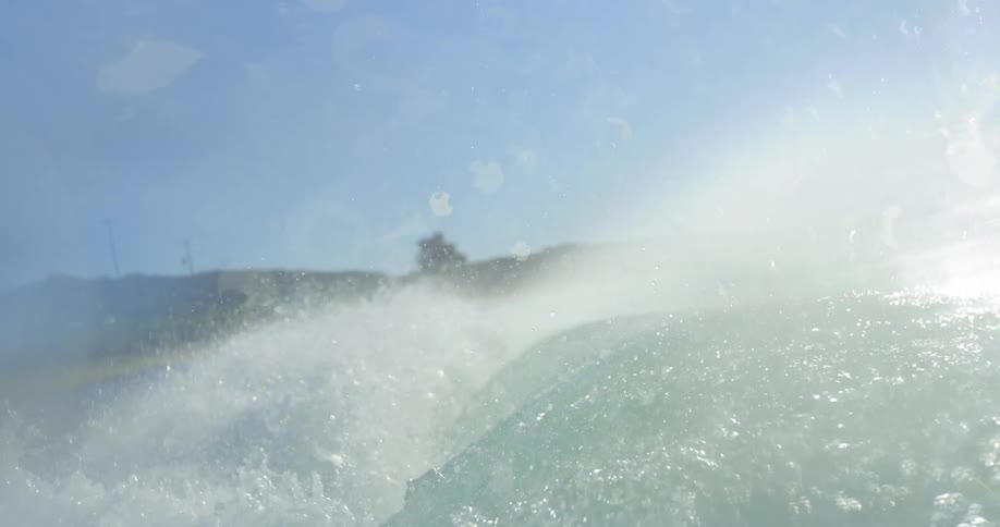 Ocean wave breaks against a coast and camera goes below the surface of a body of water